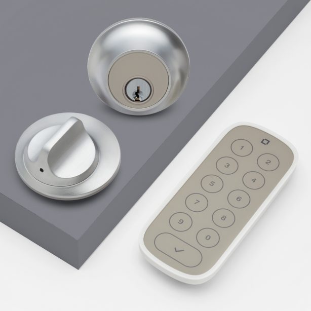 A deadbolt lock on gray door next to gray and white numbered keypad