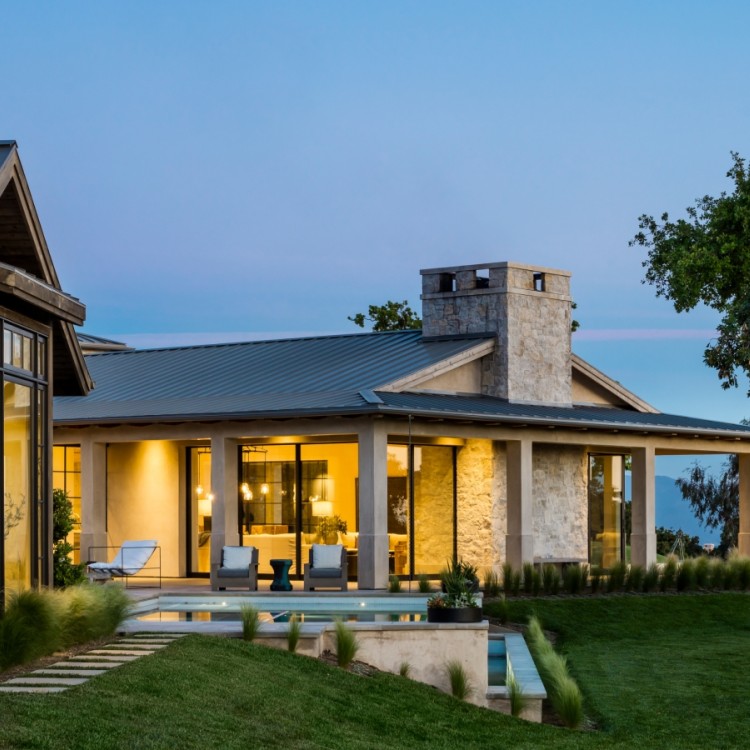 Exterior of a house in the evening, with lights on inside.
